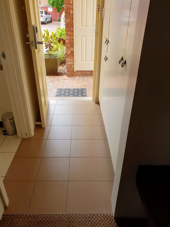 Un couloir carrelé qui mène à une porte.