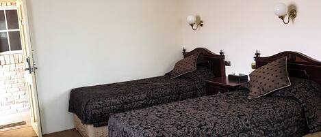 A room with two single beds, a small table, and a ceiling light.