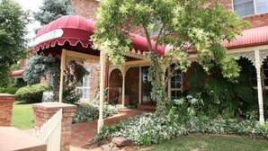 A traditional brick building with a red awning labeled "RESTAURANT" and a covered porch with columns. - Australian Heritage Motor Inn (Dubbo)