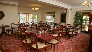 A dining area with multiple tables and chairs, large windows, and a chandelier. - Australian Heritage Motor Inn (Dubbo)
