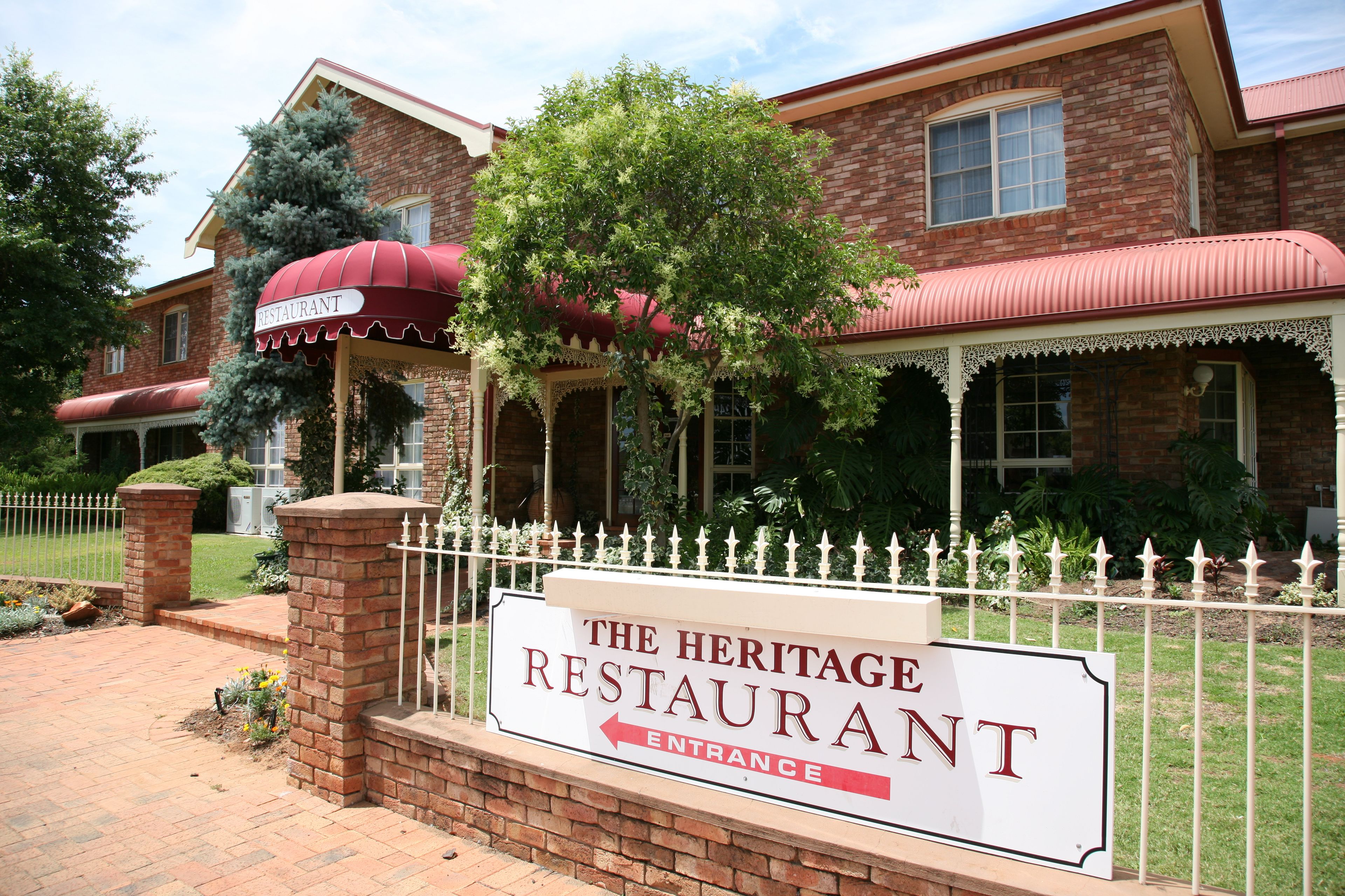 A brick building with a red awning and a sign indicating 'The Heritage Restaurant' with an entrance arrow.