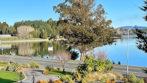 A lake with a boat, trees, and a road with a curve. - Lakewood Lofts (Te Anau)