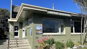 A building labeled "Lakefront Backpackers" with a reception area, a staircase, and a number "48" on the facade. - Lakewood Lofts (Te Anau)