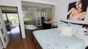 A bedroom with a floral bedspread, a large mirror, and a painting on the wall.