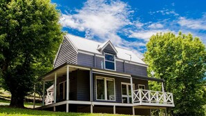 A two-story house with a porch, large windows, and a sloped roof.