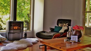 A cozy room with a fireplace, a leather chair, a wooden table, and a vase with flowers.