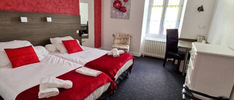 Ein Hotelzimmer mit zwei Betten, einem Sessel, einem Schreibtisch und einer Heizung.