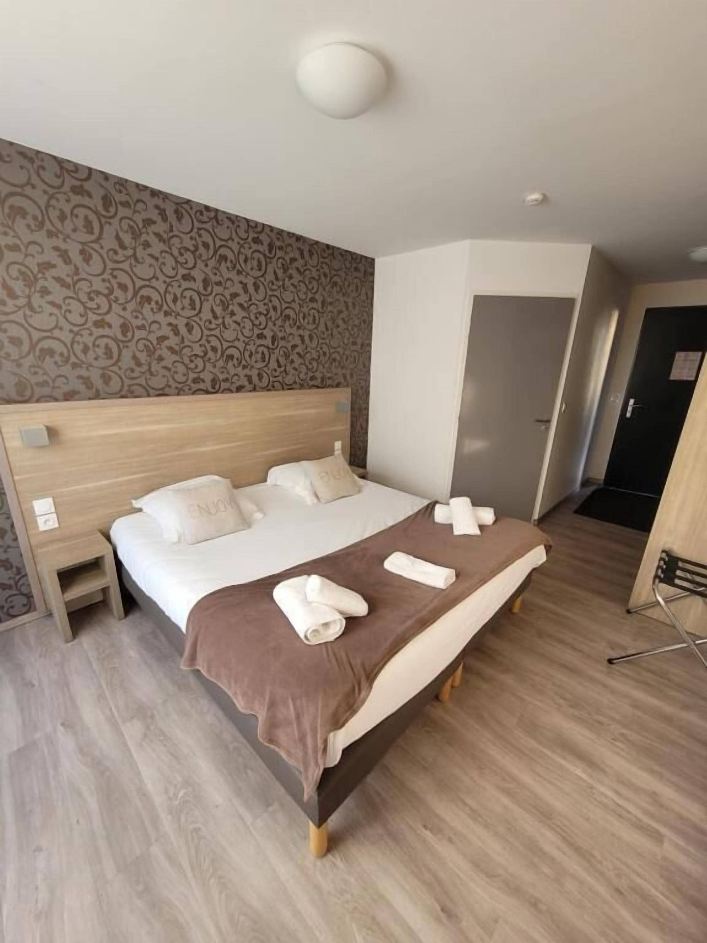 Une chambre d’hôtel avec un lit, une table de chevet, une porte et une chaise.