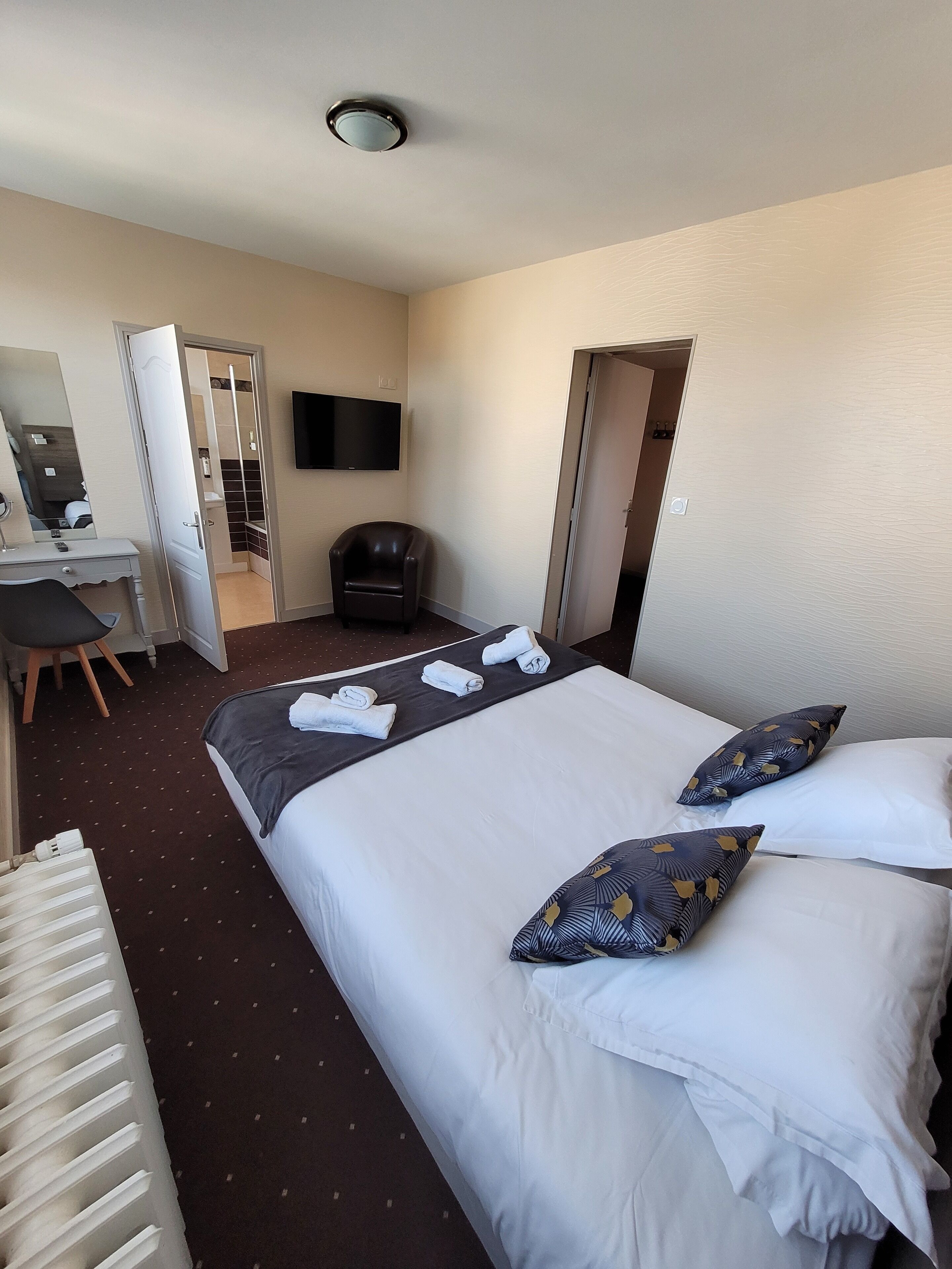 Une chambre d’hôtel équipée d’un lit, d’un bureau, d’une chaise, d’une télévision et d’une armoire.