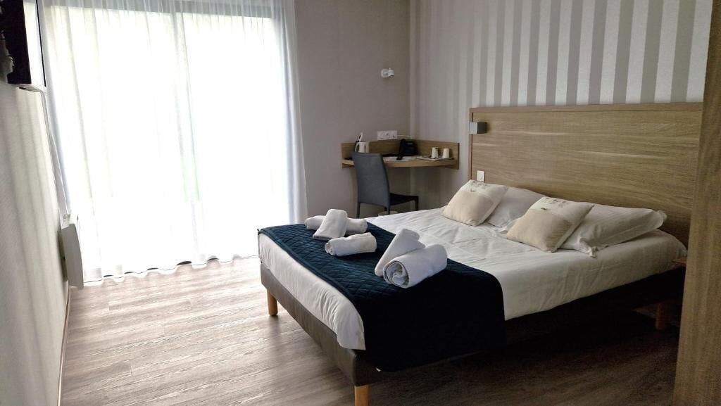 Une chambre d’hôtel avec un lit, un bureau et une chaise.