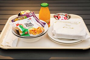 A tray with food items including a bottle of orange juice, a bowl of pasta, and a plate of toast. - Caboolture Central Motor Inn (Caboolture)