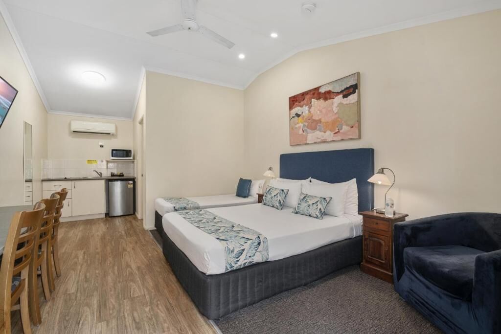 A hotel room with a bed, bedside tables, a desk, and a chair.