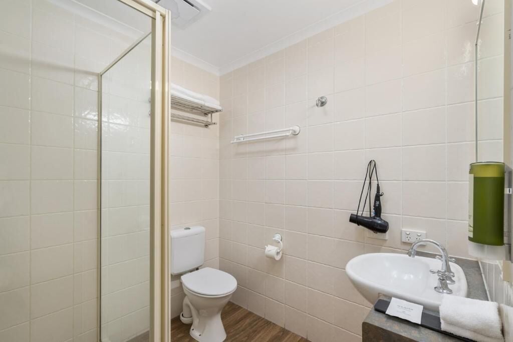 A bathroom with a toilet, sink, and shower area.