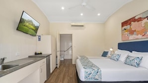 A compact hotel room with a bed, bedside table, and a television mounted on the wall. - Caboolture Central Motor Inn (Caboolture)