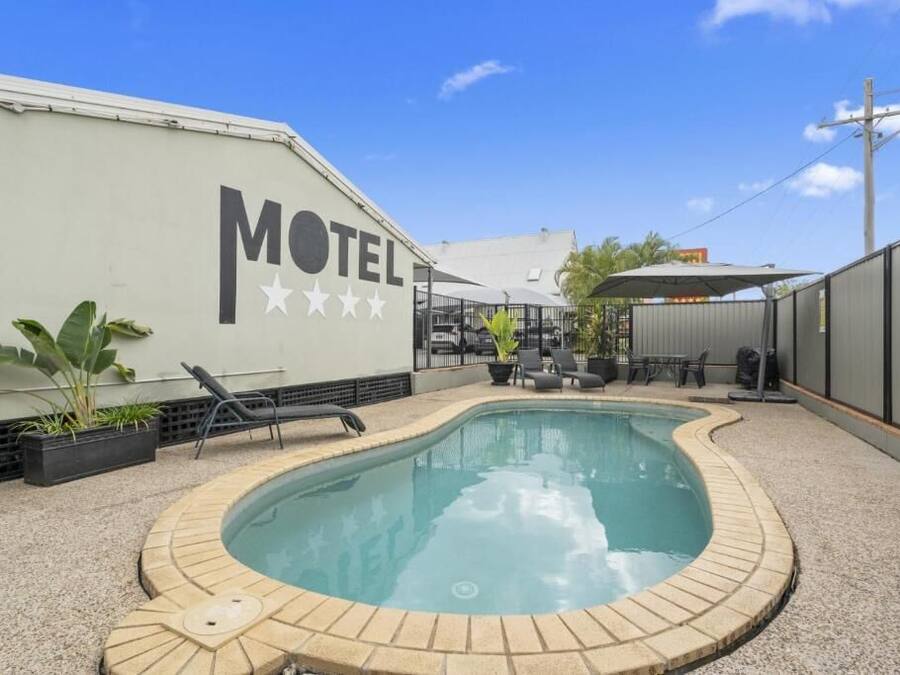 Un motel doté d’une piscine, de chaises longues et d’un espace patio.