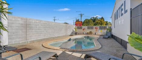 Una piscina al aire libre, camas de piscina gratis, sombrillas