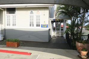 A building with a sign indicating an office, a red curb, and a planter with plants. - Caboolture Central Motor Inn (Caboolture)