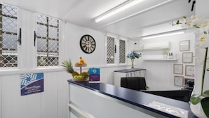A reception area with a desk, chairs, a clock, and a sign indicating a collection by Best Western. - Caboolture Central Motor Inn (Caboolture)