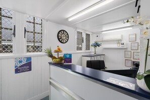 A reception area with a desk, chairs, a clock, and a sign indicating a collection by Best Western. - Caboolture Central Motor Inn (Caboolture)