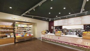 A food counter with a menu, a display of muffins, cakes, and pastries, and a refrigerated section with various drinks. - Days Inn by Wyndham Taunton (Taunton)
