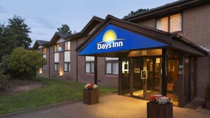 A Days Inn hotel with a brick facade, a blue awning, and a well-lit entrance. - Days Inn by Wyndham Taunton (Taunton)