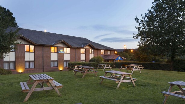 A Days Inn with multiple picnic tables arranged in a grassy outdoor area. - Days Inn by Wyndham Taunton (Taunton)