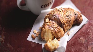 A croissant and a cup of coffee on a textured surface. - Days Inn by Wyndham Watford Gap (Northampton)