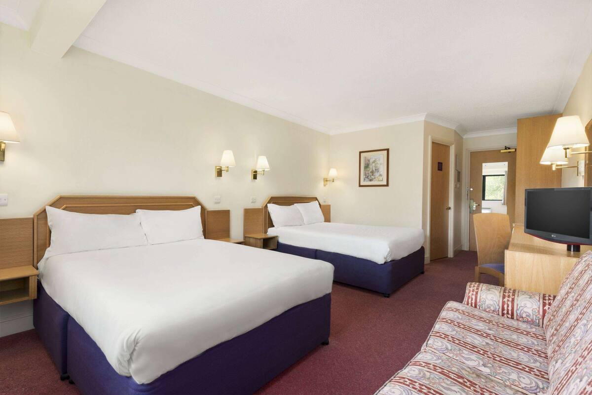 Ett hotellrum med två sängar, en TV och en soffa.