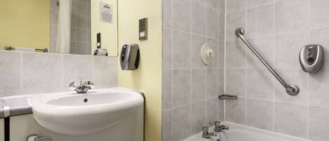 A bathroom with a sink, mirror, shower, and grab bars.