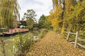 A narrow canal with a narrowboat docked on the left, a stone bridge in the background, and a wooden fence on the right. - Days Inn by Wyndham Watford Gap (Northampton)