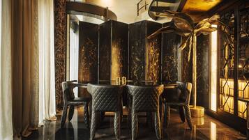 A luxurious interior with a round table and four chairs, a decorative plant, and a large window with a view.