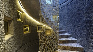 A spiral staircase with a textured wall and a metal fence.
