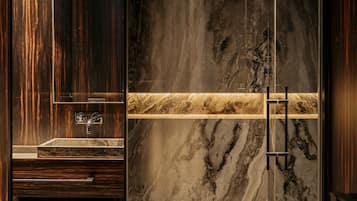 A modern bathroom with a marble vanity, a large mirror, and a glass shower enclosure.