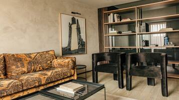 Een moderne woonkamer met een gestreept bankje, een salontafel, een boekenkast en een kunstwerk in een lijst aan de muur.