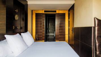A hotel room with a large bed, a wardrobe, and a bathroom visible through an open door.