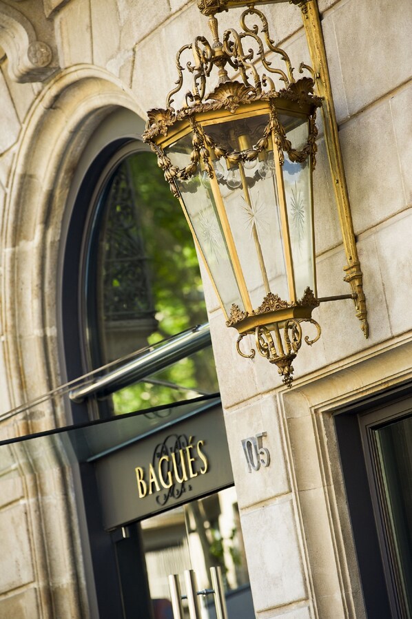 A building entrance with a gold ornate street lamp and a sign reading "BAGUES". - Hotel Bagues a Small Luxury Hotels of the World (Barcelona)
