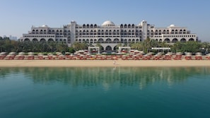 A large hotel with multiple floors, a central courtyard, and a beach area with sun loungers and umbrellas.