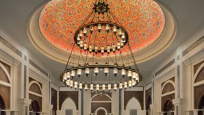 Een weelderig interieur met een centraal gelegen zwembad, gedetailleerde kroonluchters en ingewikkelde muurdecoraties.