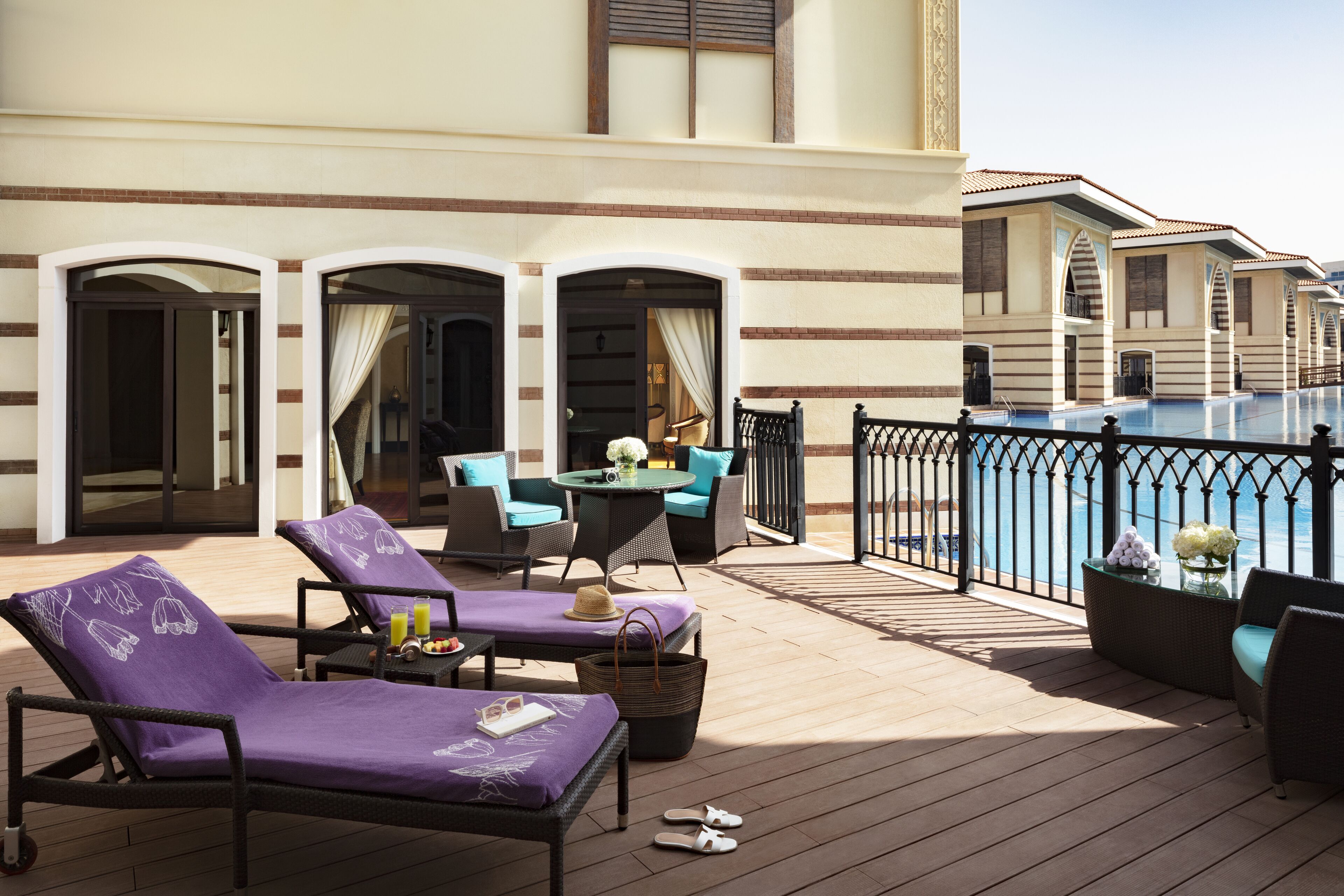 Une terrasse avec des chaises longues, une table et une vue sur une piscine.