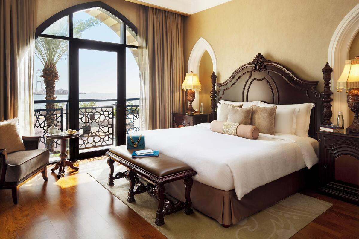 Une chambre d’hôtel avec un grand lit, une chaise, une petite table et une vue sur l’eau.