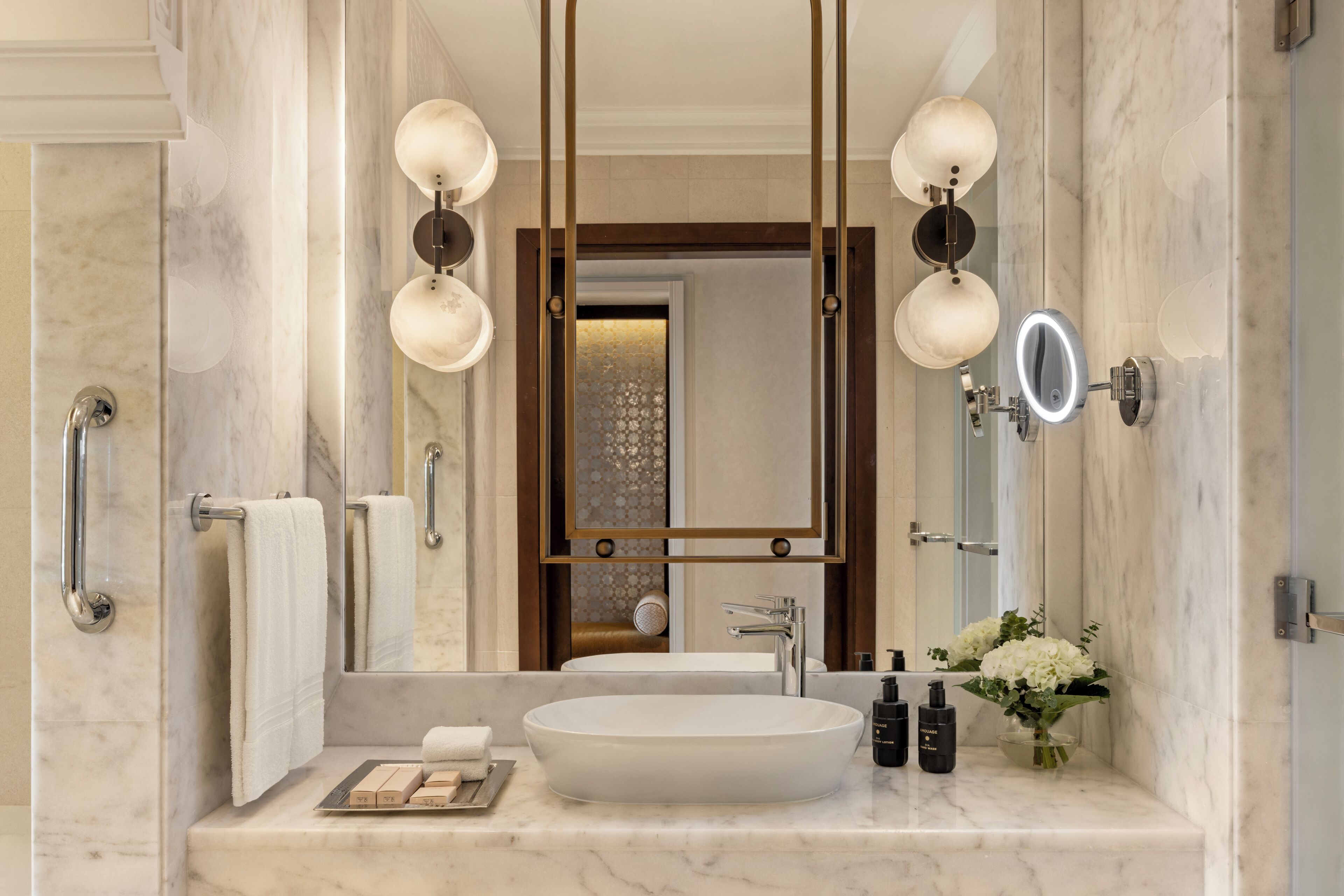 A bathroom with a large mirror, a round sink, and a towel rack.