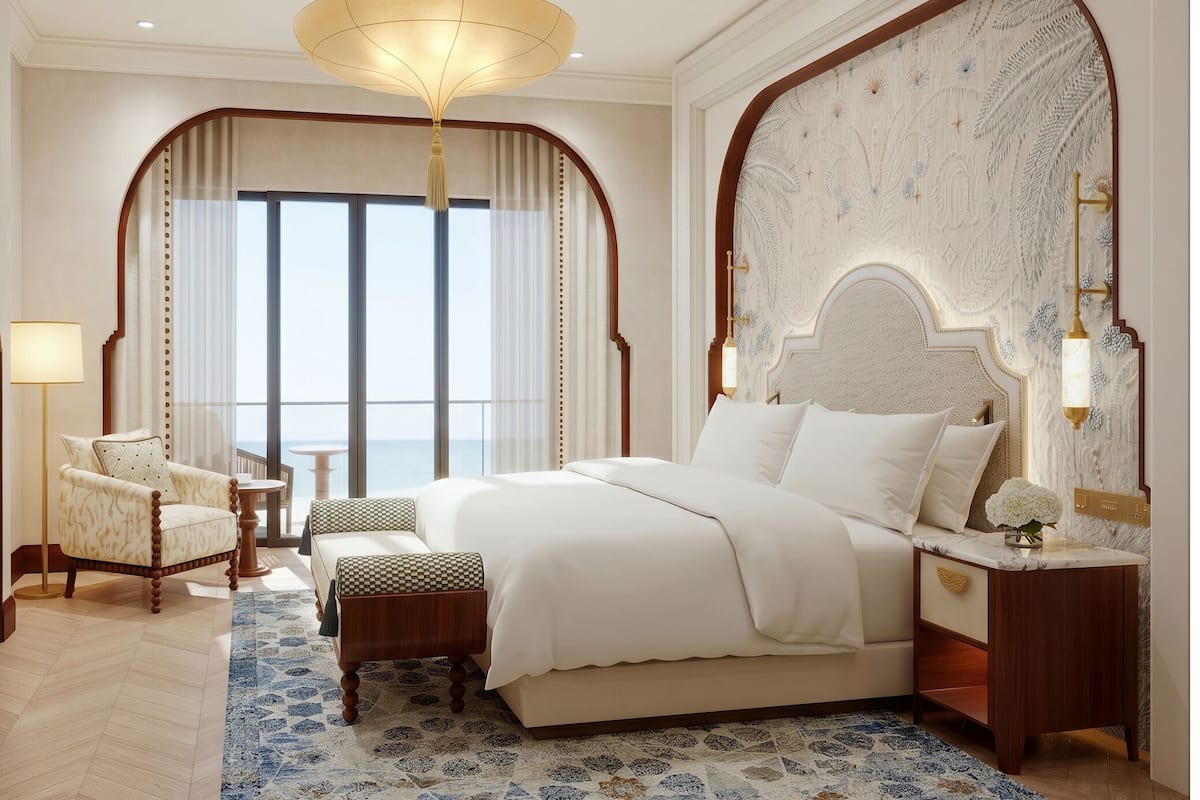 Une chambre d’hôtel avec un grand lit, une chaise, une petite table et une vue sur la mer.