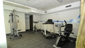 A gym with cardio machines, weight equipment, and a wall mural. - Hotel Alameda Centro (Soria)