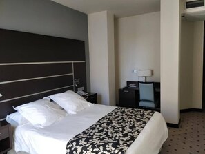 A hotel room with a large bed, a desk, a chair, and a nightstand. - Hotel Alameda Centro (Soria)