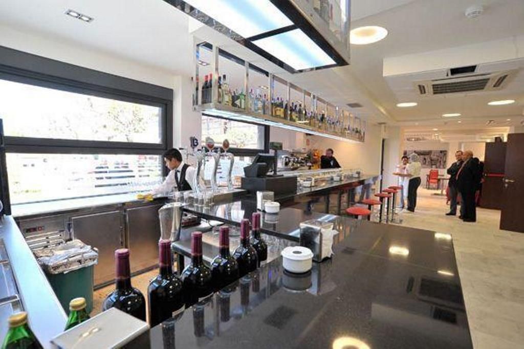 Un moderno bar con una barra pulida, botellas de vino y un ventanal grande.