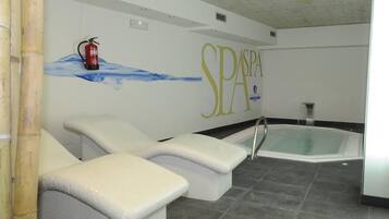 Zona de spa con dos sillones reclinables, un jacuzzi y un extintor colgado en la pared.
