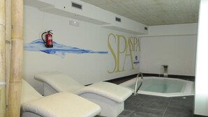 Zona de spa con dos sillones reclinables, un jacuzzi y un extintor colgado en la pared.