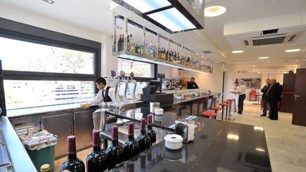 Un moderno bar con una barra pulida, botellas de vino y un ventanal grande.