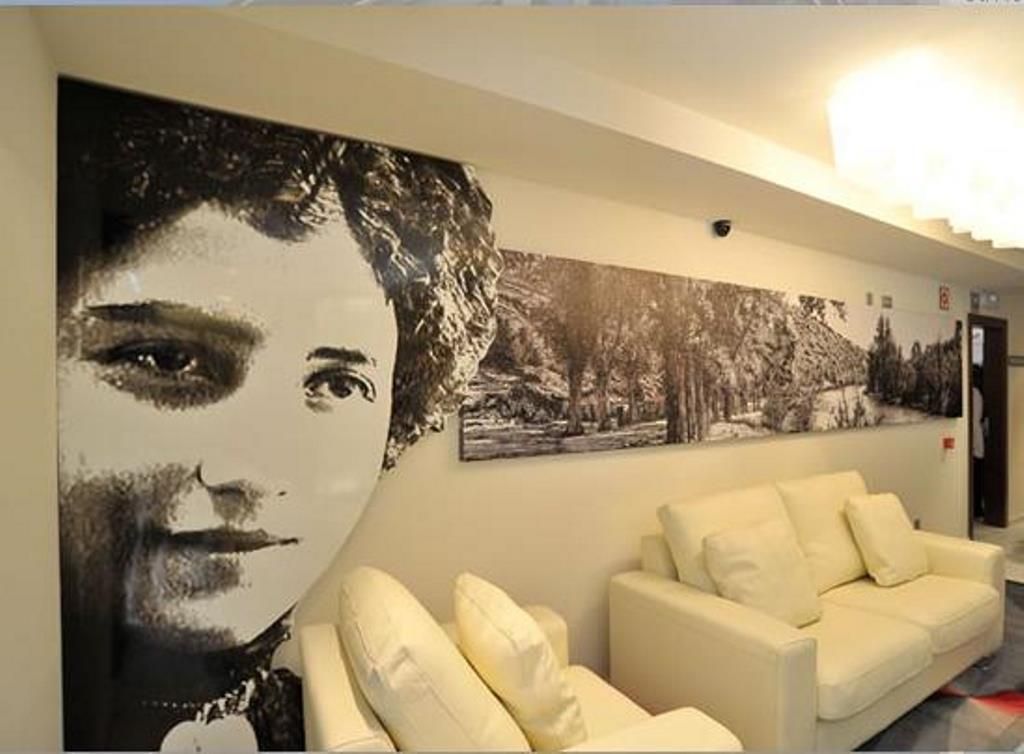 Un vestíbulo de hotel con un mural grande en la pared, un sofá blanco y una lámpara en el techo.