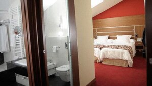 A hotel room with a bed, a bedside table, a nightstand, a window, and a bathroom with a toilet and sink. - Hotel Alameda Centro (Soria)